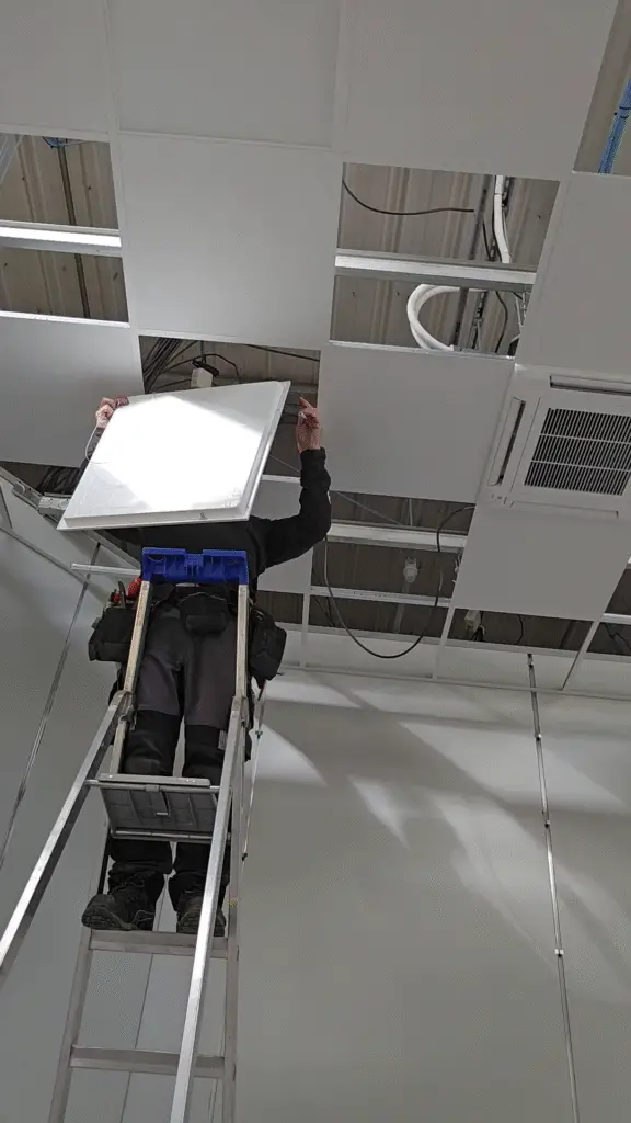Technicien ERA installant un plafonnier LED sur échelle