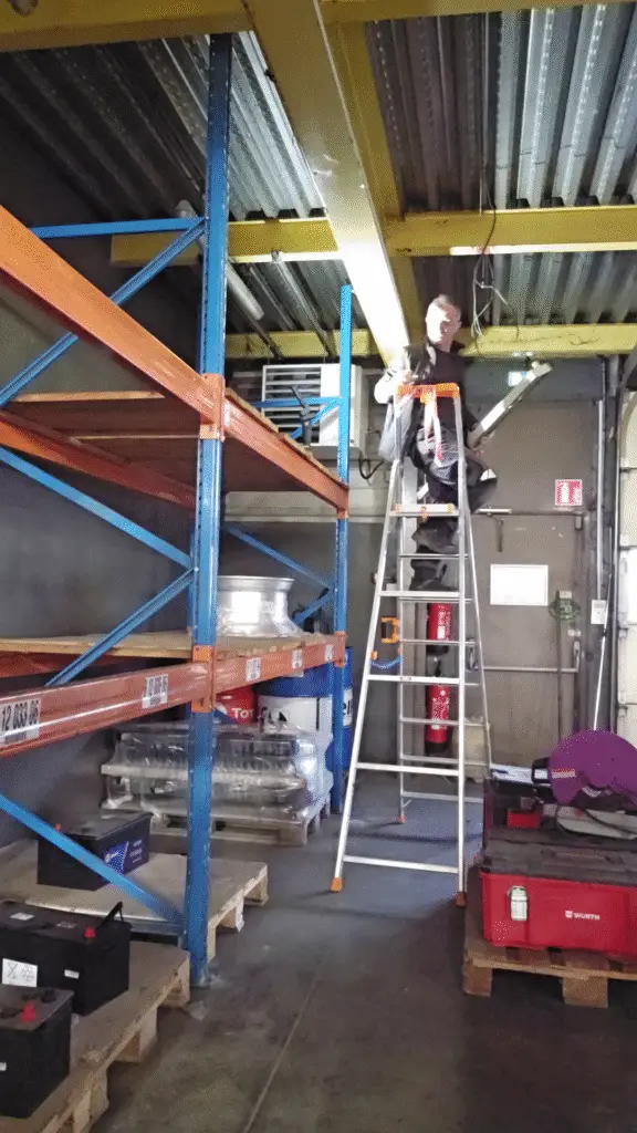 Technicien ERA installant un éclairage LED entre rayonnages d'entrepôt