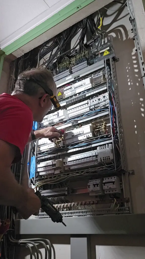 Électricien ERA intervenant en sécurité sur un ancien tableau électrique avant sa dépose